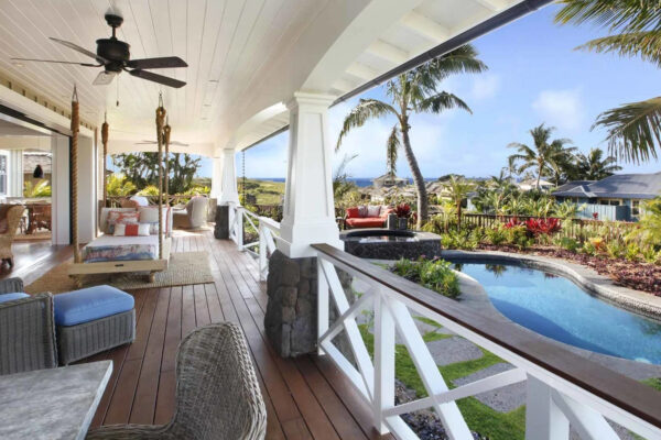 A porch with a view of the pool and palm trees.