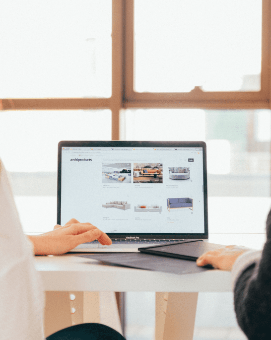 Two people sitting at a table with a laptop.