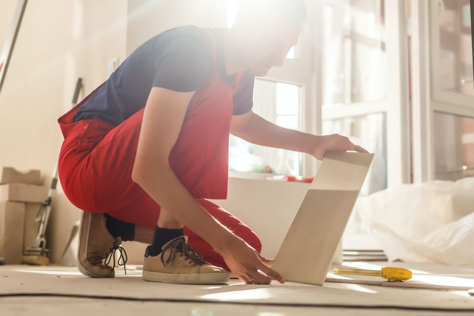 A man kneeling down on the floor looking at an open laptop.